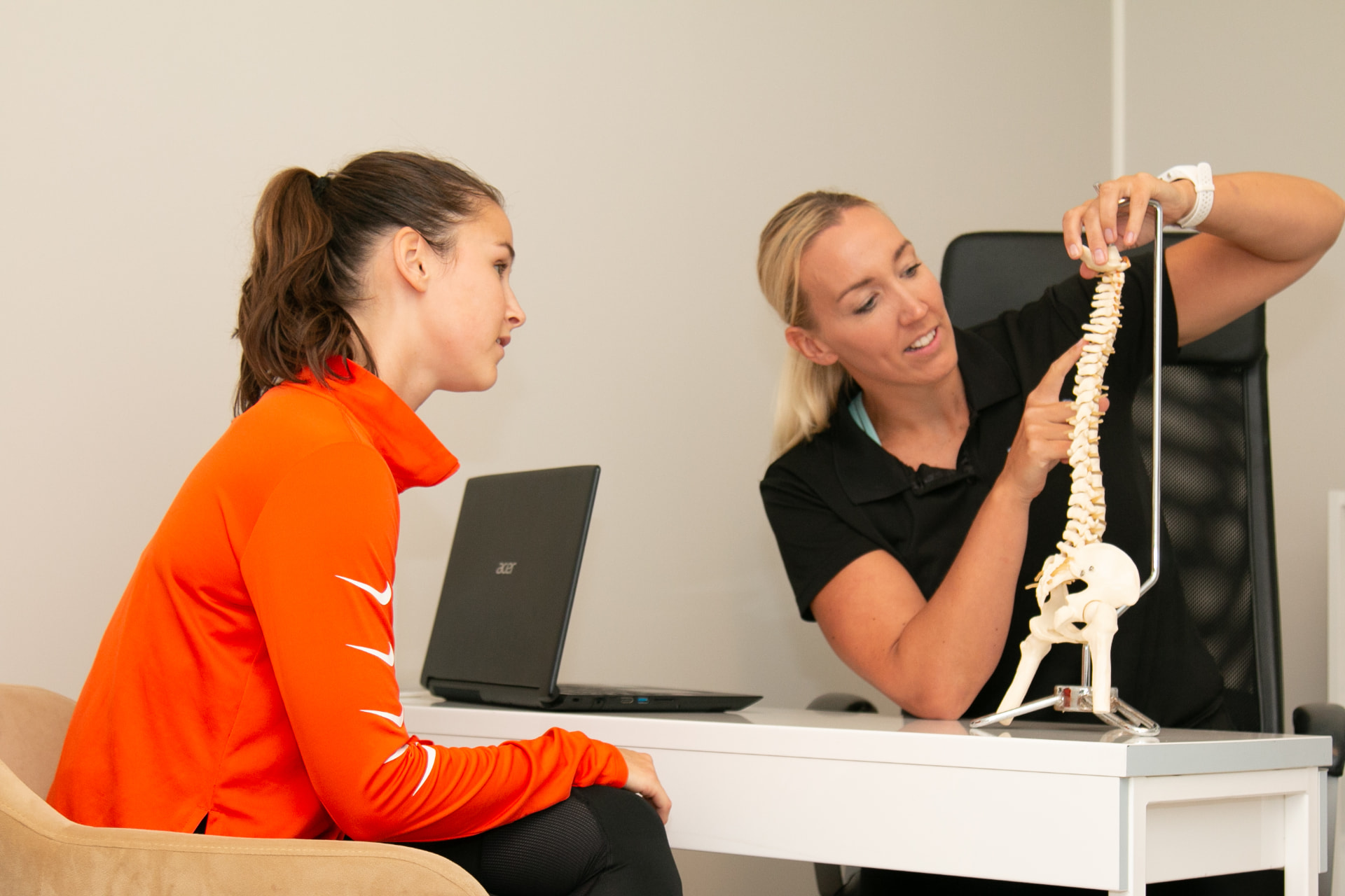 Fysioterapeut forklarer ryggmodell for en pasient hos Trimfit